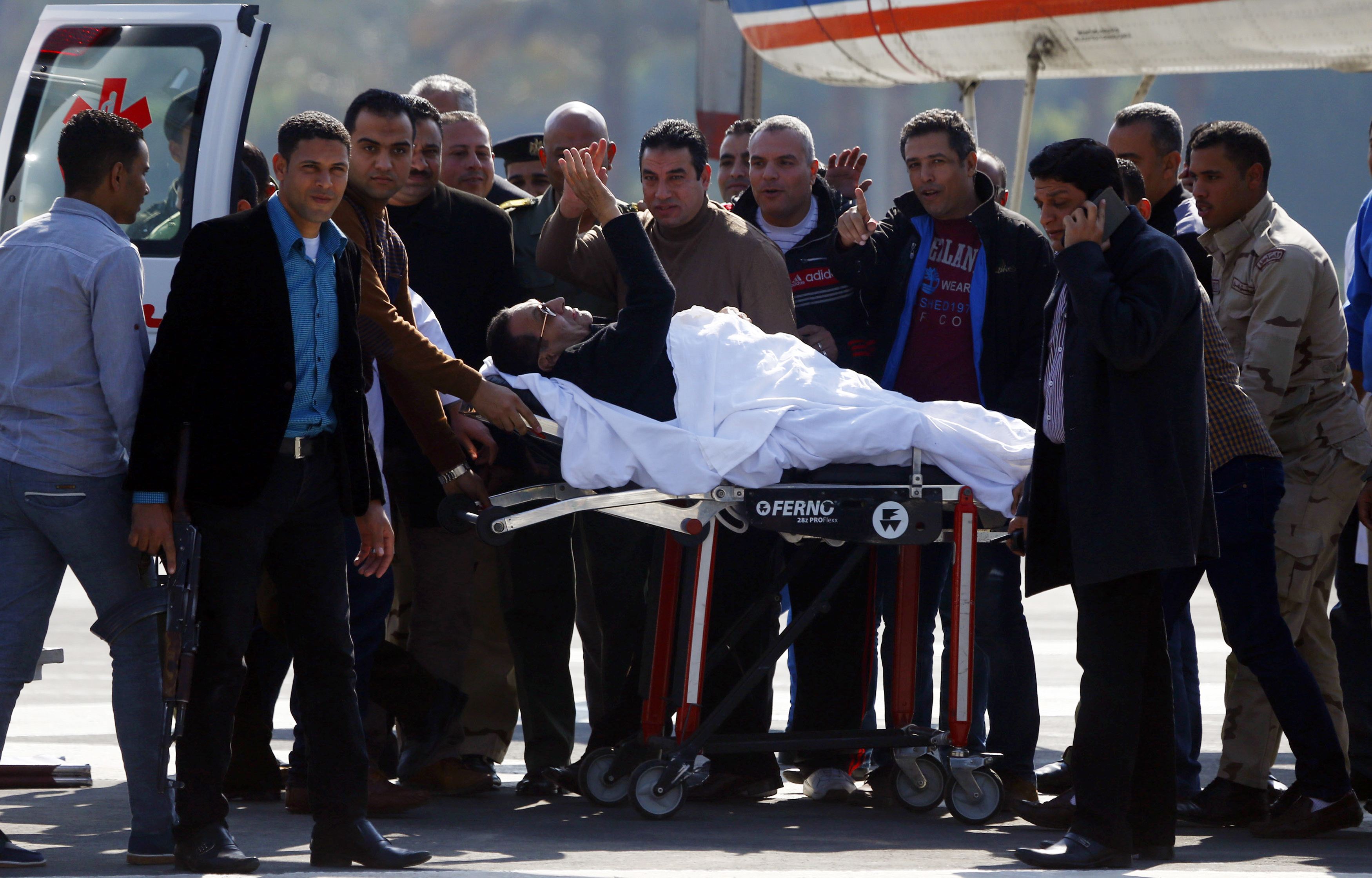 Former Egyptian President Hosni Mubarak waves to his supporters from his stretcher as he returns to Maadi military hospital in Cairo
