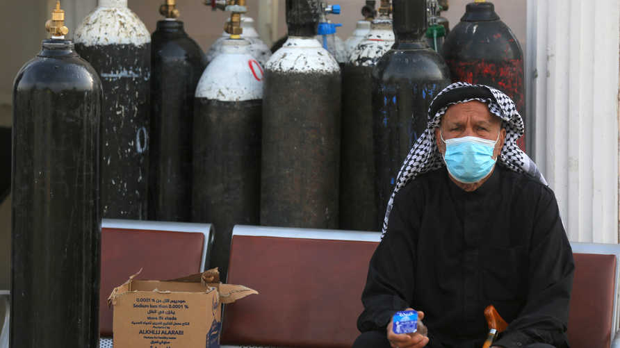 An Iraqi man waits next to oxygen bottles for his wife who is a patient with COVID-19 at the Ibn Al-Khatib Hospital in Baghdad, on April 25, 2021, after a fire erupted in the medical facility reserved for the most severe coronavirus cases. - At least 23 people died when a fire broke out in a coronavirus intensive care unit in the capital of Iraq, a country with long-dilapidated health infrastructure facing mounting COVID-19 cases. (Photo by AHMAD AL-RUBAYE / AFP)